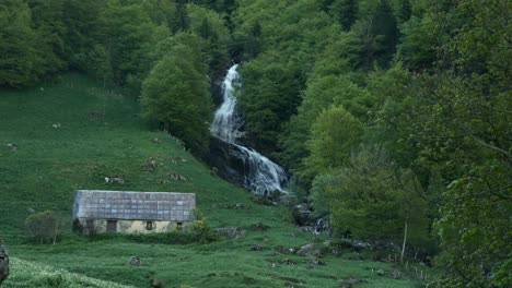 view on a barn close to a water fall in the cirque de gavarnie, a unesco site in the french pyrenees.