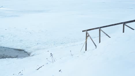 Aufnahme-Einer-Schneebedeckten-Treppe-Durch-Ein-Eisloch-In-Einem-Zugefrorenen-See-Tagsüber-Im-Schneereichen,-Kalten-Winter