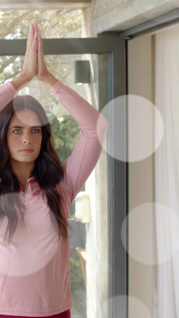 Video vertical: Mujer entrando y centrándose, levantando los brazos en posición de oración por la salud junto a una puerta de cristal.