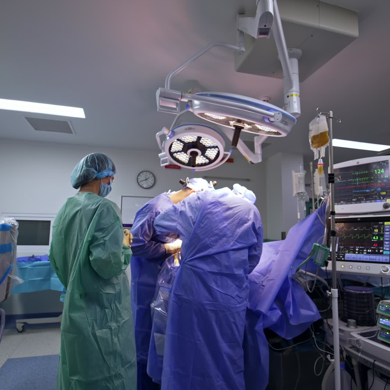 Two cooperating neurosurgeons bent over the operational table. Assisting doctors stand on the sides. Neurosurgery in modern surgical room