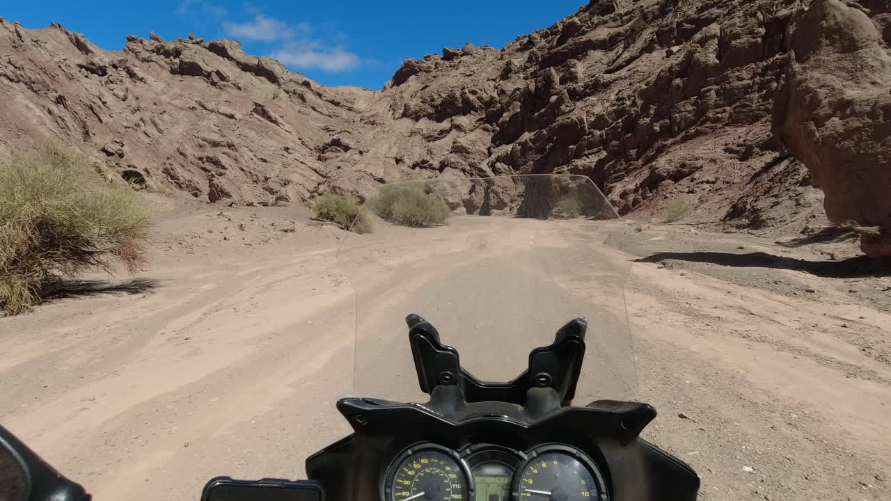 Moto POV: Motorcyclist rides alone in narrow sandstone badlands canyon