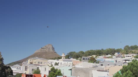 General-view-of-cityscape-with-houses,-mountain,-trees-and-blue-sky