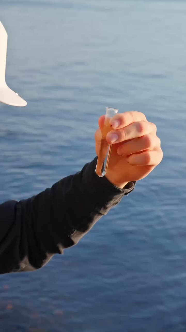 Close up of hand holding water vial with lake in background, test procedure shown