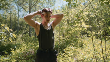 front view of warrior standing in dense forest surrounded by green leaves and branches, tying white headband around forehead, sweat glistening on skin under dappled sunlight illuminating scene
