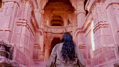 niña entrando en la arquitectura del antiguo templo hindú de piedra roja desde un ángulo único en el día