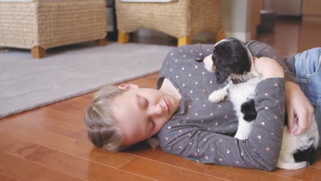 little girl hugging, and petting her adorable puppy on a wooden floor