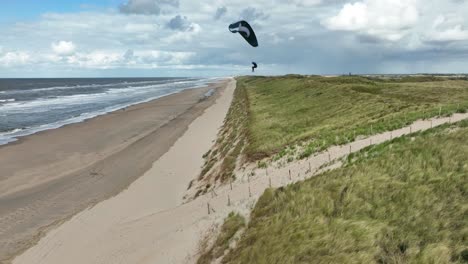 statyczne ujęcie drona z lotu ptaka przedstawiające paralotnię jadącą na silnym wietrze na słonecznej plaży