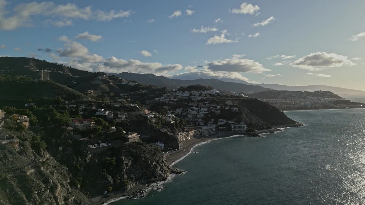 Ripresa con drone in avvicinamento della costa di Almuñécar durante il giorno, con il Mar Mediterraneo e il paesaggio urbano di Granada, in Spagna