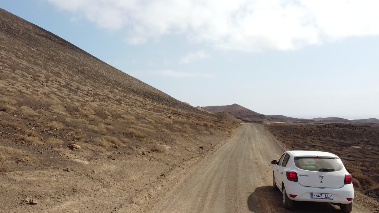 Auto che guida su una strada sterrata attraverso un paesaggio desertico