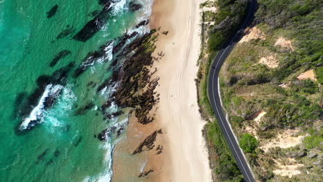 toma de drones en aumento de la playa de shelly y las rocas de wellington con la carretera costera y las olas del océano en nambucca heads nueva gales del sur australia