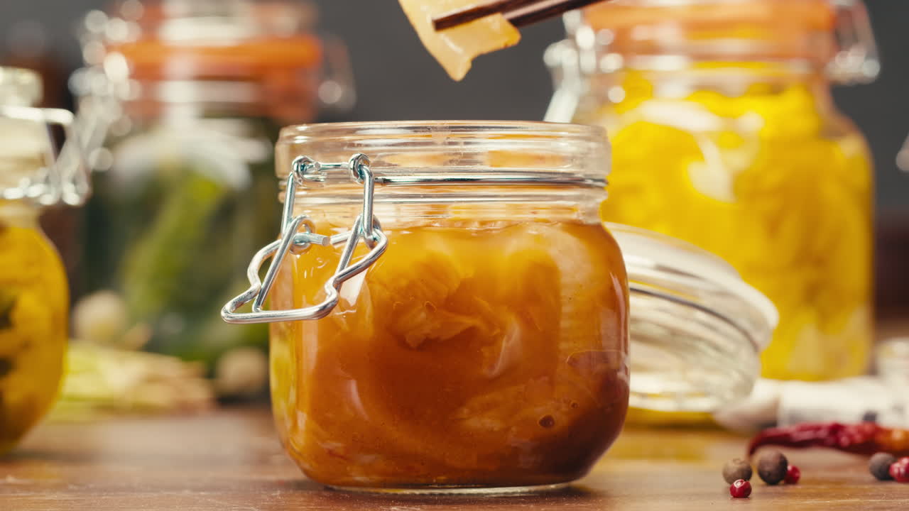 Fermented food in glass cans on table close-up. Preservation of vegetables in glass jars. Fermentation preserved mini corns, kimchi, cucumbers, mushrooms with spices.
