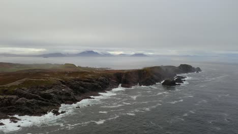 aaerial ascend of malin head’s rugged coast on a foggy morning