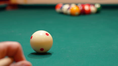 low angle closeup of cue ball as person breaks rack of 8 ball powerfully on pool table with green felt and cue stick bending as both solid and stripe balls scatter, close bridge hand, no faces in bar