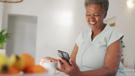 Happy-senior-african-american-woman-using-smartphone-at-home