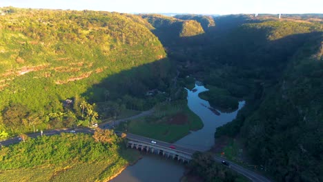 Aerial-tilt-up-revealing-landscape-and-road,-Waimea-Beach-at-golden-hour,-Hawaii