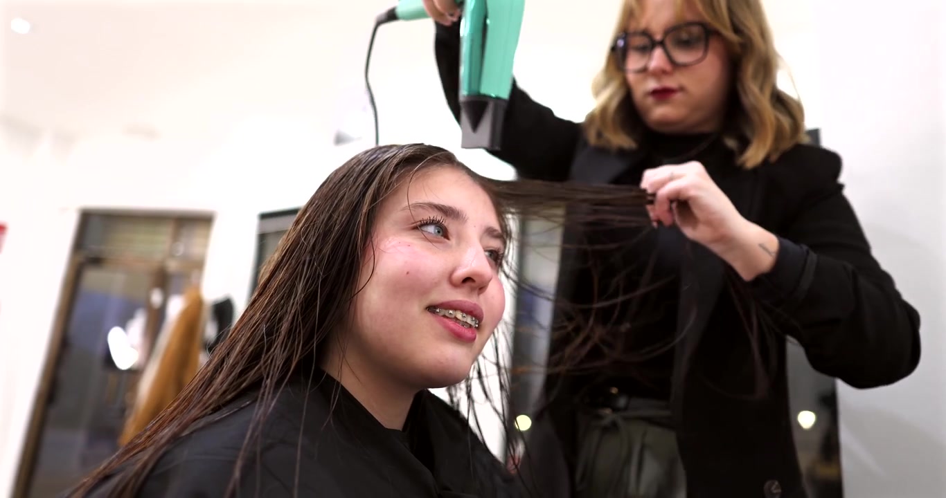 Hairdresser Drying Young Woman's Hair in a Salon