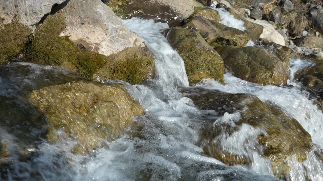 Primo piano di una cascata cristallina che scende a cascata sulle rocce al rallentatore.