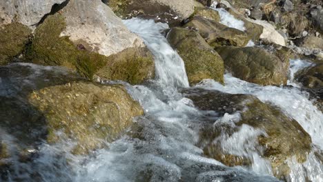 close-up view of a crystal-clear waterfall cascading over rocks in slow motion.