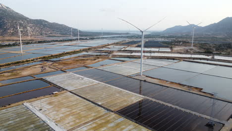 aerial view of saline pond farm with windmill wind turbine green power energy supply sustainable farming in vietnam asia