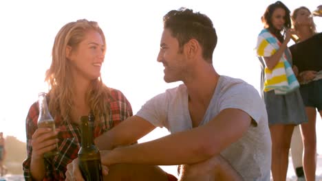 couple drinking a beer on the beach