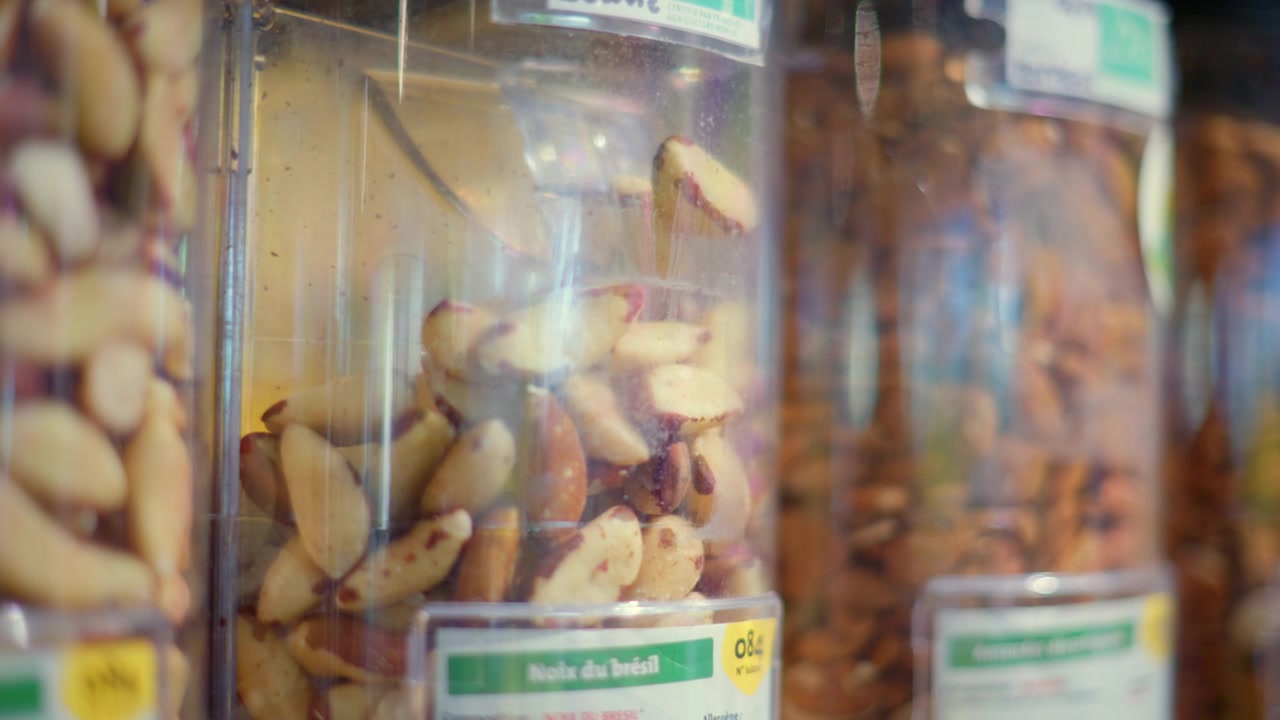 Brazil nuts filling a transparent dispenser at a healthy food grocery store, promoting zero waste and sustainable shopping