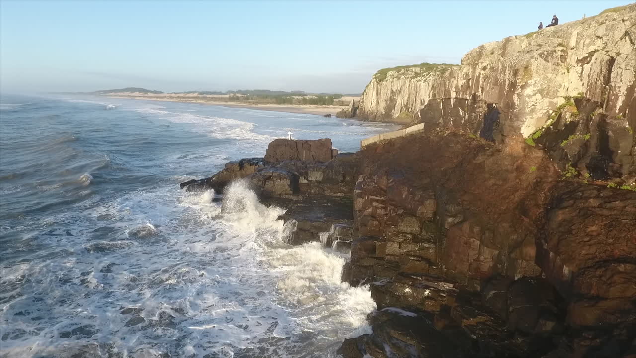 Sunrise at ocean and wave splashing in the rocks, aerial footage, Torres, Brazil
