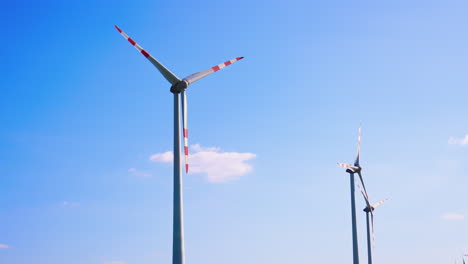 wind turbines against a clear blue sky. two large wind turbines are rotating smoothly under a clear blue sky during a sunny day, showcasing renewable energy