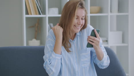 portrait of happy business woman enjoy success on mobile phone at home office. closeup joyful girl reading good news on phone in slow motion. surprised lady celebrating victory on phone in apartment.