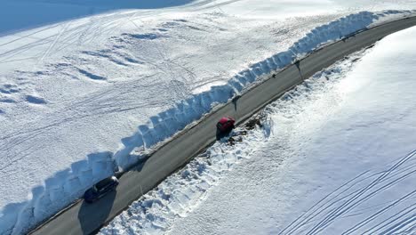 Un-Automóvil-Rojo-Que-Conduce-A-Lo-Largo-De-La-Carretera-Vikafjell-Rv-13---Antena-De-Ojo-De-Pájaro-Que-Sigue-Al-Automóvil-En-El-Paisaje-Invernal-Desde-Arriba---Clip-Corto-De-Movimiento-Rápido