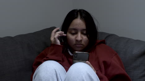 close up shot of a young girl sitting on a couch and checking her phone