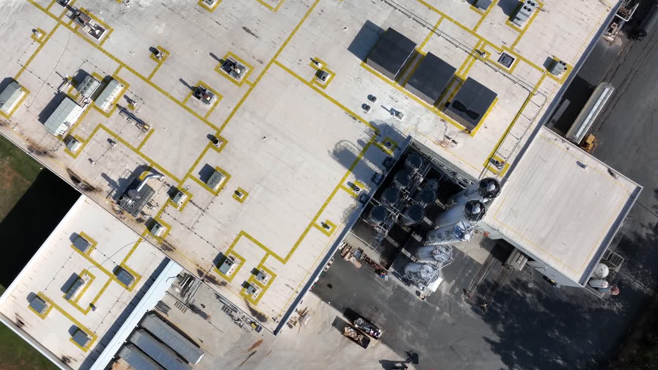 Aerial view of American factory roof with vents ducts and machinery arranged in precise grid as bright daylight. Industrial patterns of rooftop in american town. Sunny day in fall