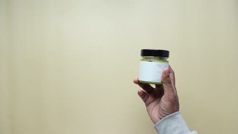 hand holding a glass jar with blank label