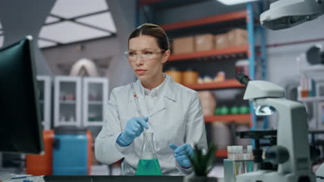 una mujer científica experimentando una muestra de fármaco en un frasco en un laboratorio médico.
