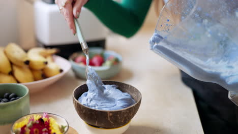 woman, hand and prepare smoothie bowl in kitchen