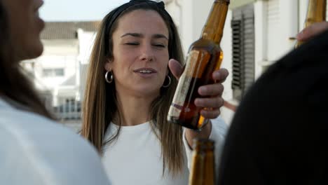 smiling woman listening friends and raising bottle to make toast