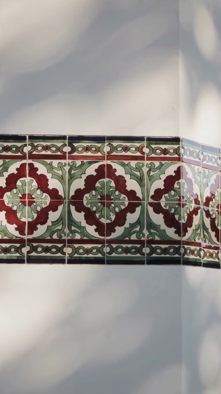 Video verticale: Telecamera che si sposta rivelando una fascia di piastrelle sull'angolo di un muro esterno, con ombre e fughe che si muovono.