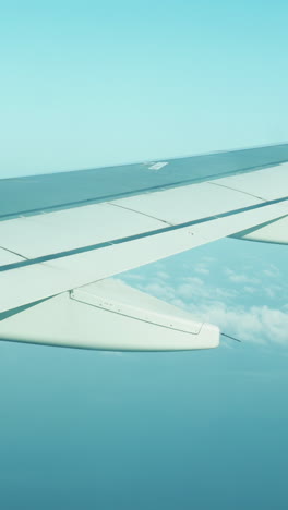 view from a plane window of the sky with the wing of the plane in shot in vertical