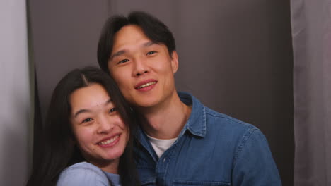 젊은 사랑하는 커플이 실시간으로 촬영된 사진 부스에서 초상화를 위해 포즈를 취하고 있습니다.