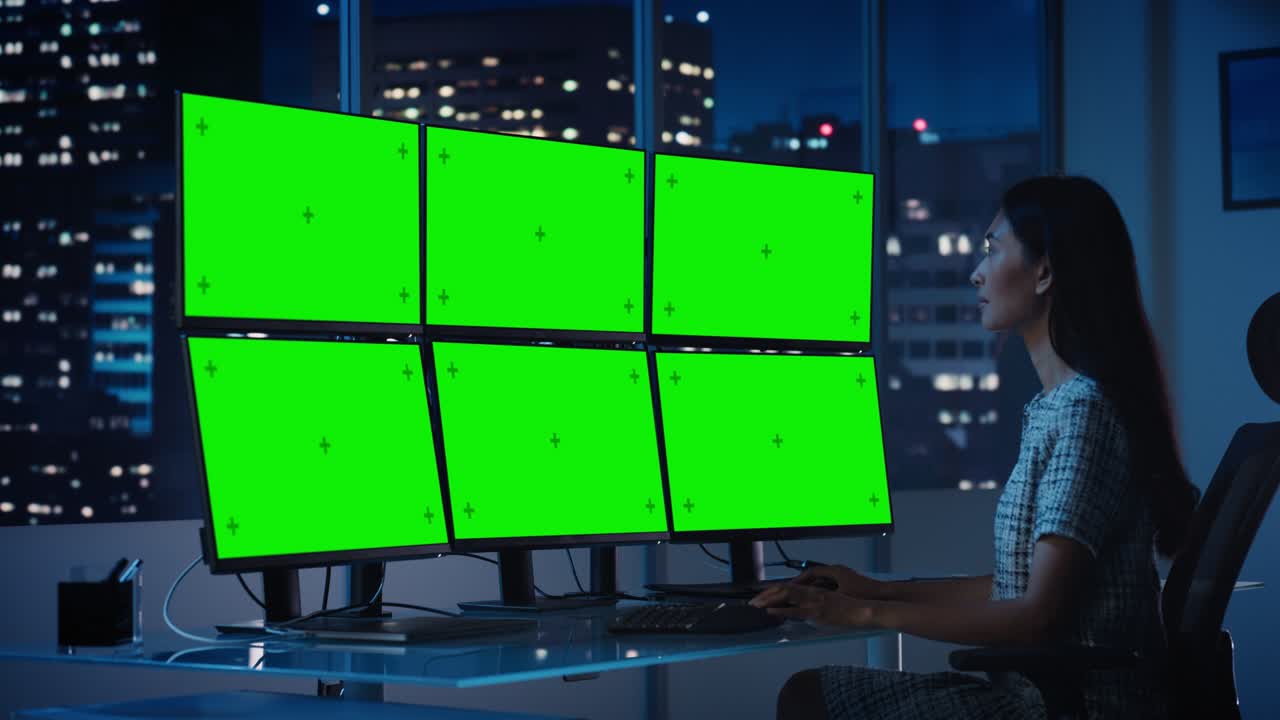 다중 모니터 워크스테이션을 가진 컴퓨터에서 일하는 금융 분석가 녹색 화면 크로마 키 모형 템플릿 디스플레이 비즈니스 여성은 저녁 늦게 투자 은행에서 일합니다.