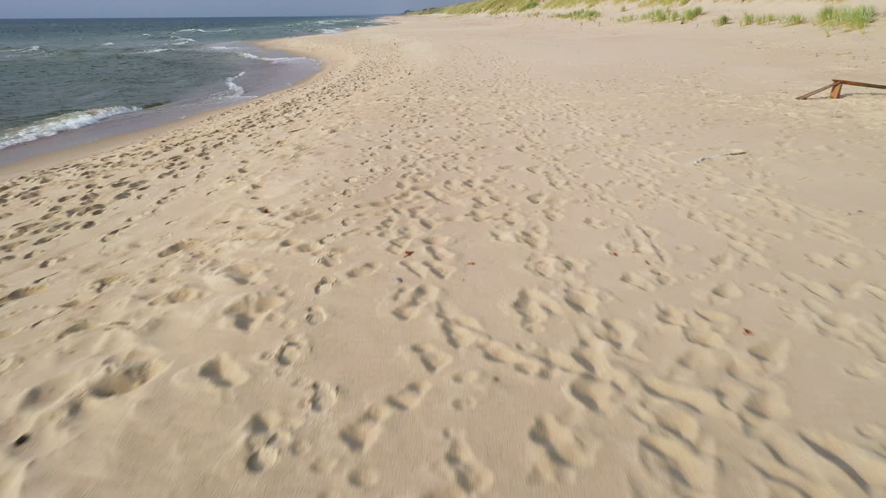 Empty sandy beach with ocean waves and footprints