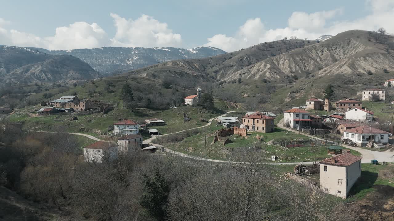 Ripresa con drone di montagne boscose innevate, tempo mite, piccolo villaggio, volando sopra la collina da sogno, video 4K, natura invernale europea