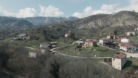 un drone disparó de las montañas del bosque con nieve, clima cálido, pequeño pueblo, volando por encima de la colina de ensueño, video 4k, naturaleza invernal europea