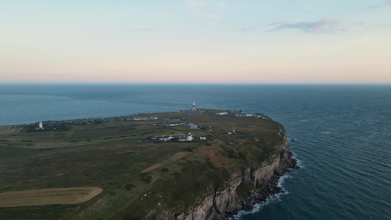 4K footage of the drone travelling towards Portland Bill's lighthouse, in Dorset England, and going over it during a beautiful sunset.