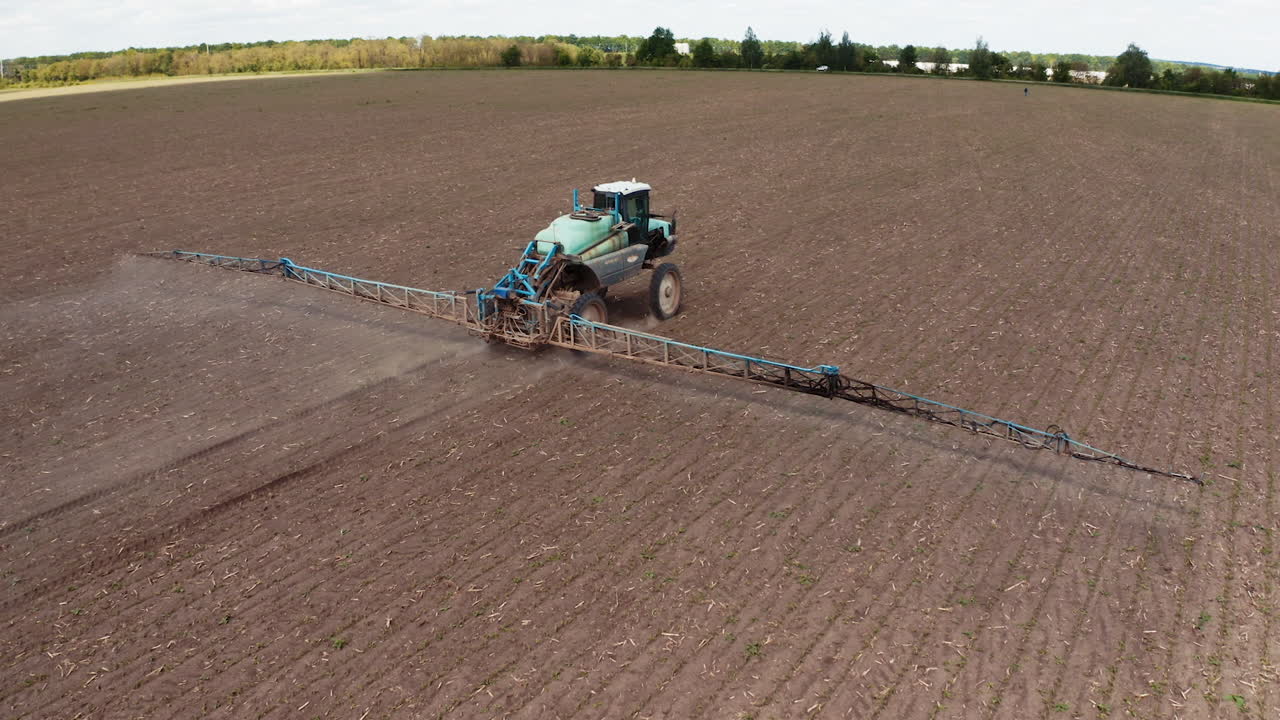 Tractor spraying field with fertilizer. Tractor spraying chemical pesticides with sprayer on the large agricultural field