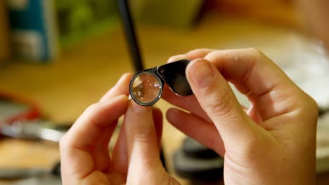 jewelry designer holding loupe magnifier in workshop 4k