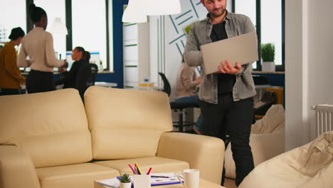 business man typing on laptop sitting on couch in start up office