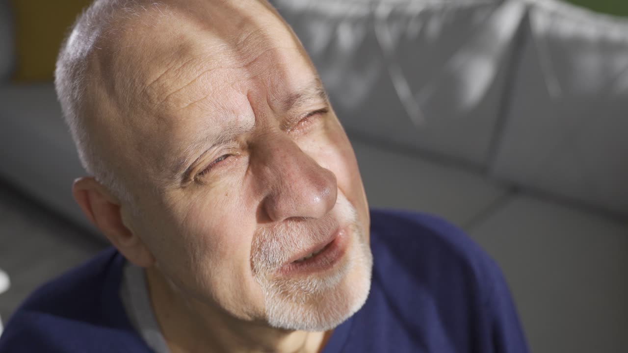 Senior depressed old man looking at camera with sad facial emotion expression.