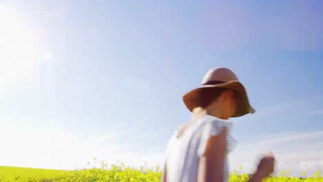 happy woman wearing hat and walking in mustard field