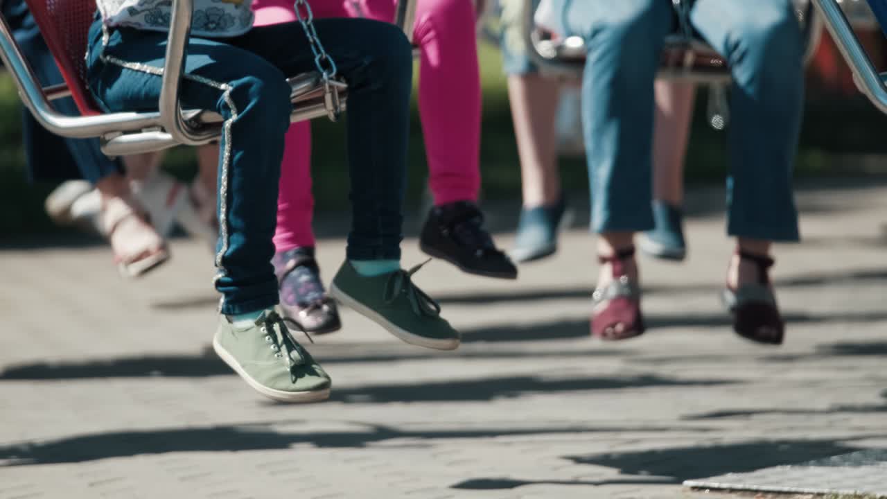 pies de niños sentados en el carrusel en la atracción del parque