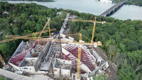 aerial view construction of a new building with high tower cranes in green area